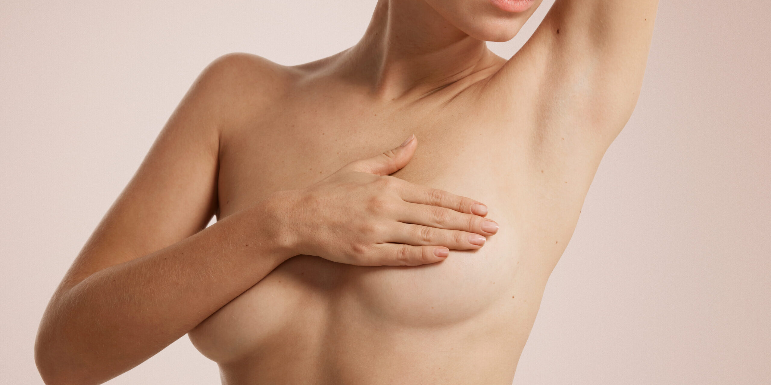 Closeup cropped portrait young woman with breast pain touching chest colored isolated on background